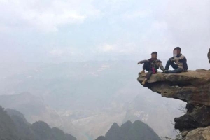Hai đứa bé ngồi vắt vẻo trên mỏm đá cao treo leo ở Hà Giang để 'thu tiền' check-in khách du lịch