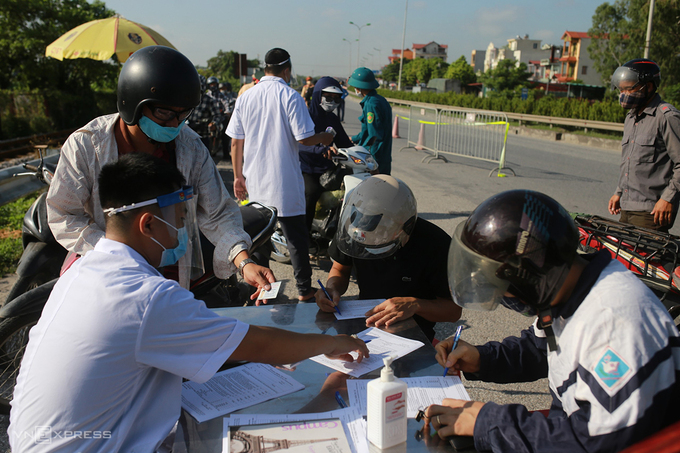 Lực lượng y tế hướng dẫn người dân vào Hà Nội tại chốt kiểm soát quốc lộ 1A - Cầu Giẽ ngày 14/7. Ảnh: Tất Định.