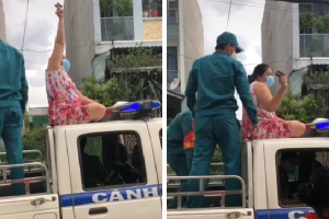 Không đeo khẩu trang, người phụ nữ còn trèo lên nóc xe cảnh sát ngồi, múa may làm loạn nơi công cộng