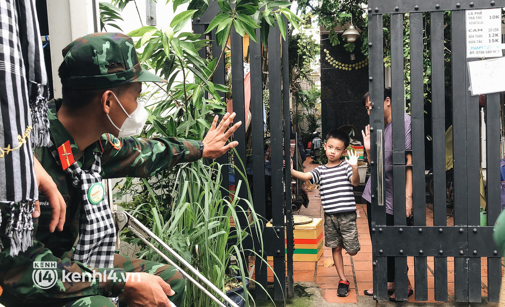 Một chiến sĩ vẫy tay chào tạm biệt hai cha con ở quận Bình Thạnh trước khi trở về đơn vị.