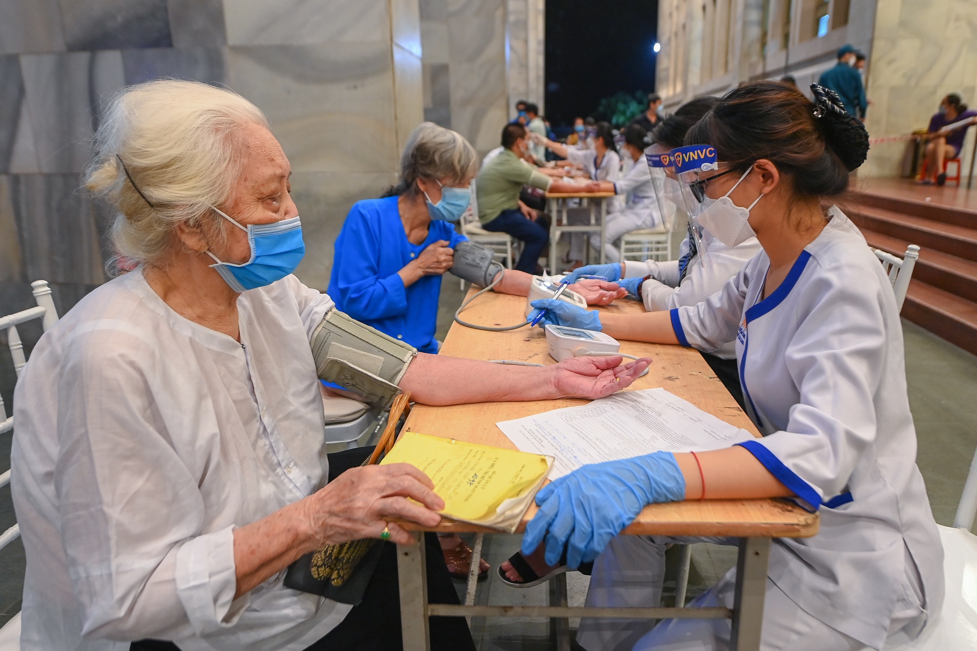 Một phụ nữ lớn tuổi được nhân viên y tế khám sàng lọc trước khi tiêm vaccine Covid-19 tại Hà Nội. Ảnh: Việt Linh