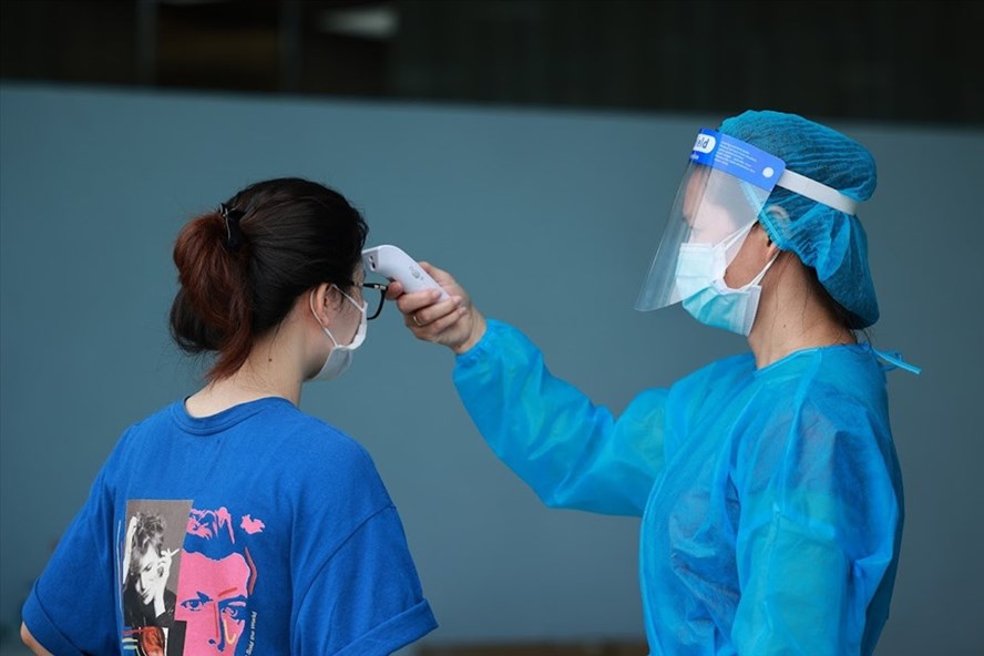 Cán bộ y tế đang đo thân nhiệt cho người dân trước khi vào khu vực tiêm vaccine COVID-19 Hà Nội. Ảnh: Hải Nguyễn.