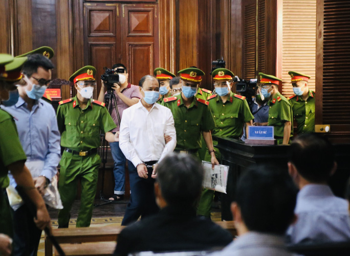 Cảnh sát dẫn giải bị cáo Lê Tấn Hùng cùng đồng phạm vào phòng xử án.