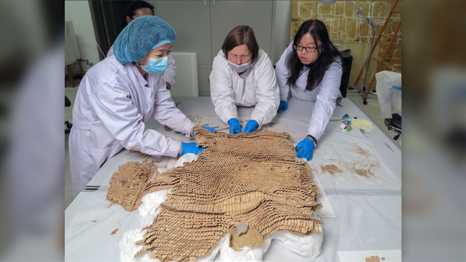  Các nhà nghiên cứu xem xét bộ áo giáp vảy da được tìm thấy trong mộ cổ Trung Quốc. Ảnh: Patrick Wertmann/Đại học Zurich.