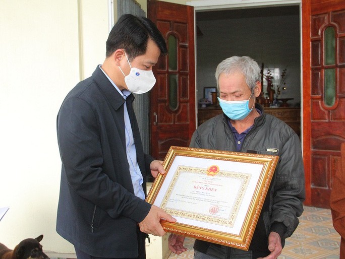 Ông Đào Xuân Yên, Trưởng ban Tuyên giáo Tỉnh ủy Thanh Hóa trao bằng khen của Chủ tịch UBND tỉnh Thanh Hóa tặng anh Trang Văn Nam cho người thân của anh.