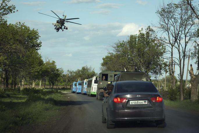 Đoàn xe buýt chở binh lính rời Azovstal có xe áp tải từ phía Nga theo sau - Ảnh: AP.