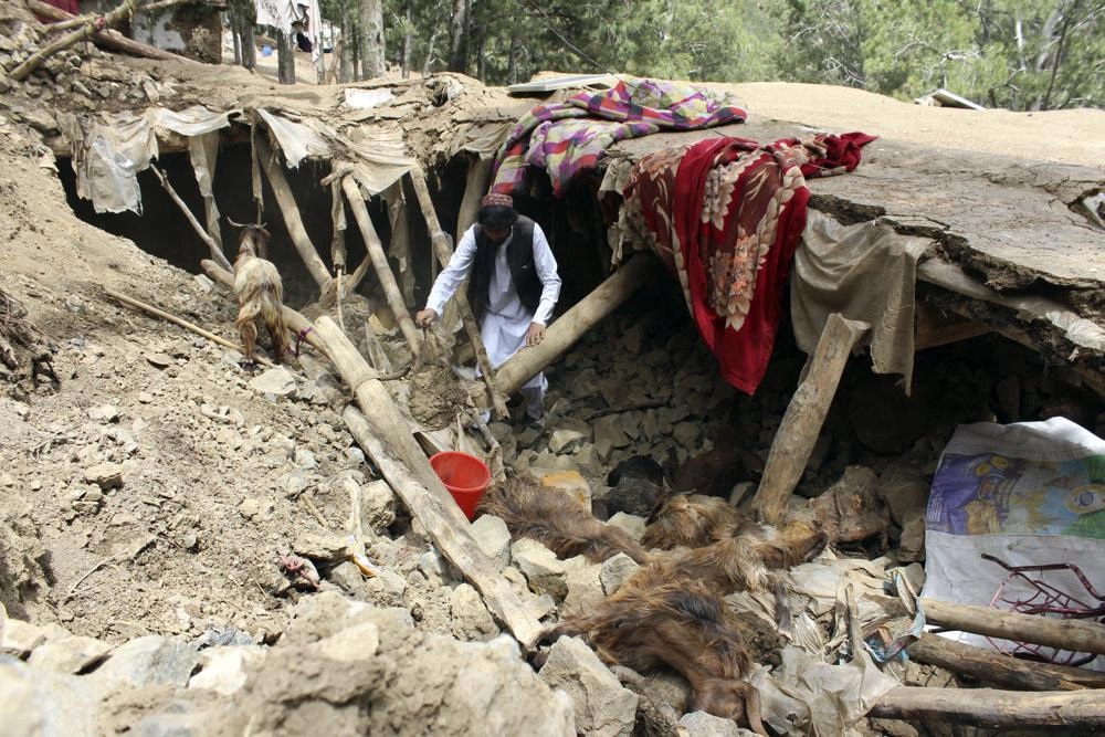 Dân làng Afghanistan thu dọn đồ đạc dưới đống đổ nát ở huyện Spera, phía tây nam tỉnh Khost hôm 22/6. Ảnh: AP.