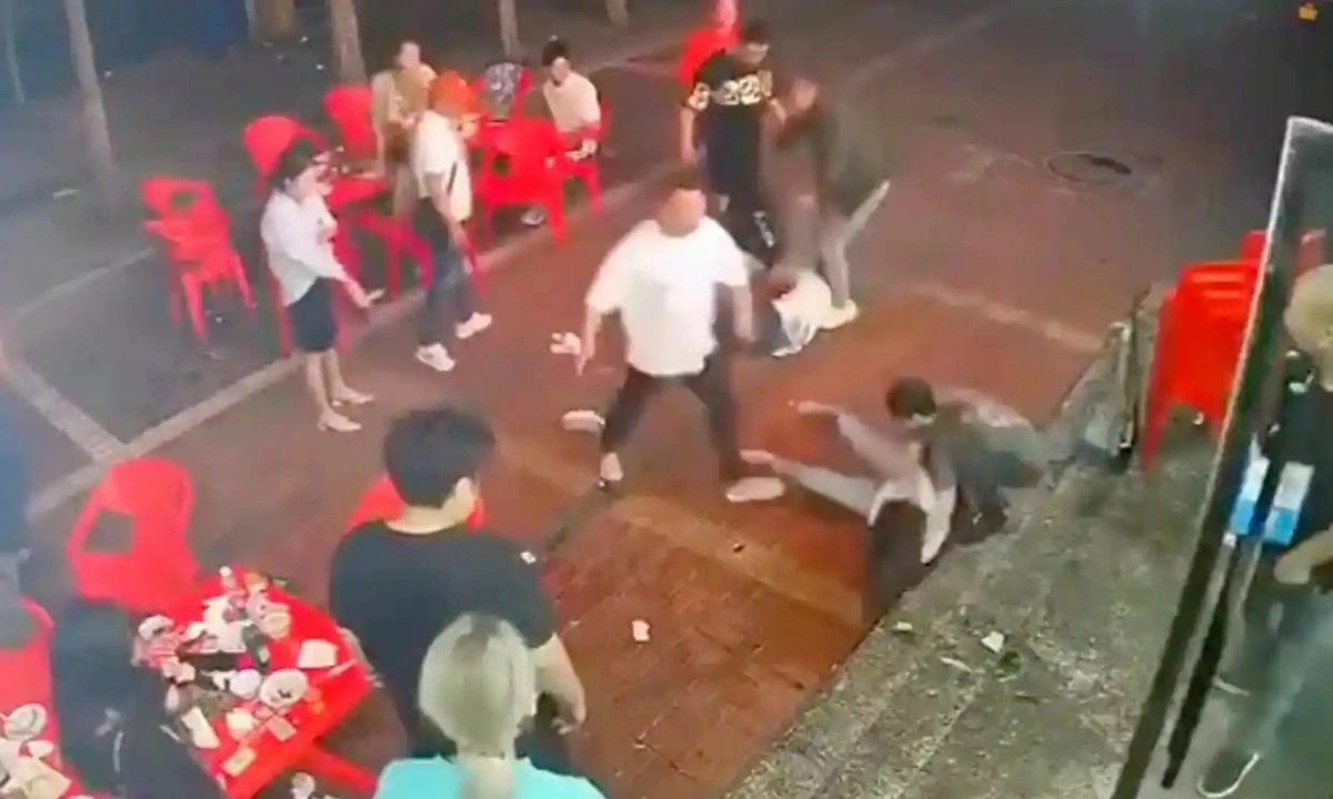 Nhóm nam giới túm tóc người phụ nữ lôi ra ngoài và đánh đập ở Đường Sơn. Ảnh: Straits Times.