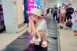 Cô gái ngồi xổm trên băng chuyền hành lý ở sân bay