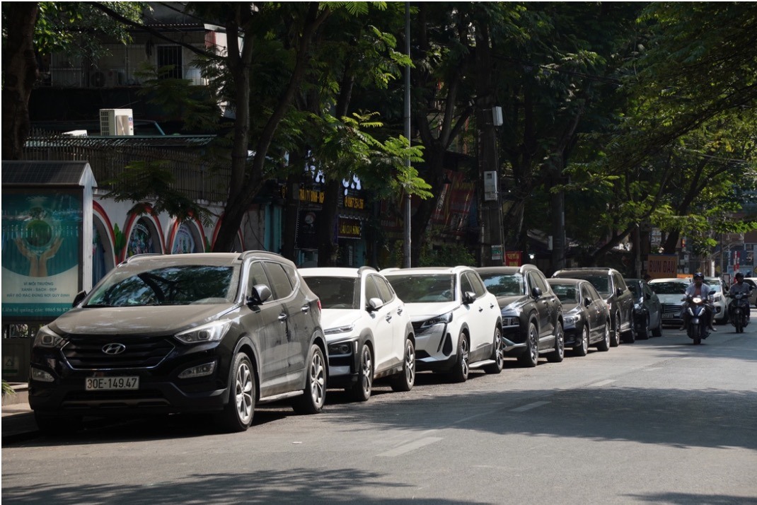 Hàng dài ôtô nối đuôi nhau đỗ dưới lòng đường phố Nghĩa Tân.