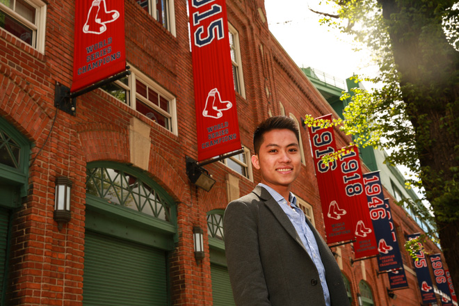 Tyler La đứng trước toà nhà treo đầy bang rôn cho chiến dịch marketing và thương hiệu cho đội bóng Boston Red Fox.